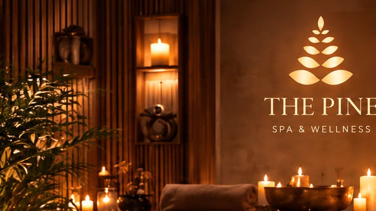 Bức tường gỗ có logo The Pine Spa & Wellness, ánh nến và chậu cây xanh