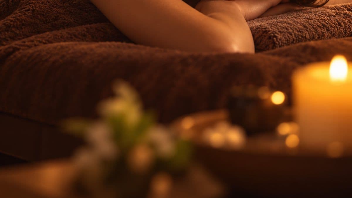Khách nằm nghỉ trên giường phủ khăn nâu, phía trước là ánh nến và hoa nhỏ