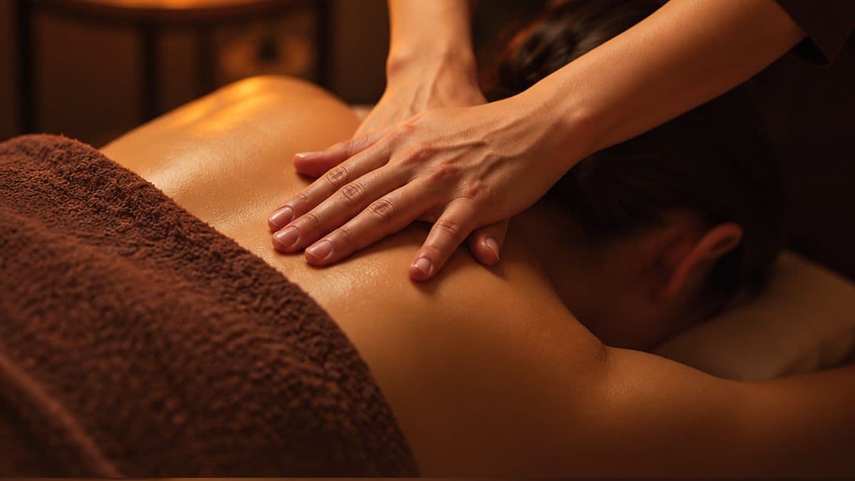 Kỹ thuật viên dùng hai tay massage lưng trên của khách nằm sấp