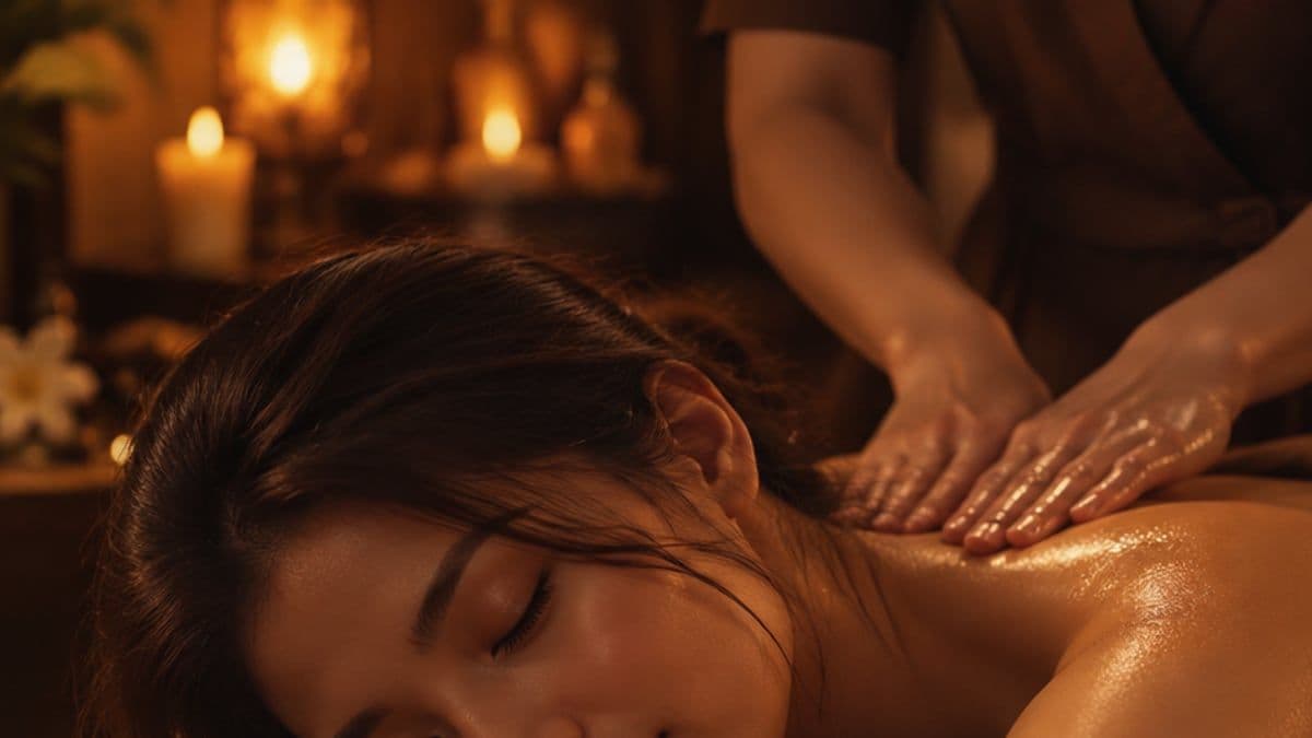 Kỹ thuật viên massage nhẹ vai và lưng trên của khách nằm nhắm mắt