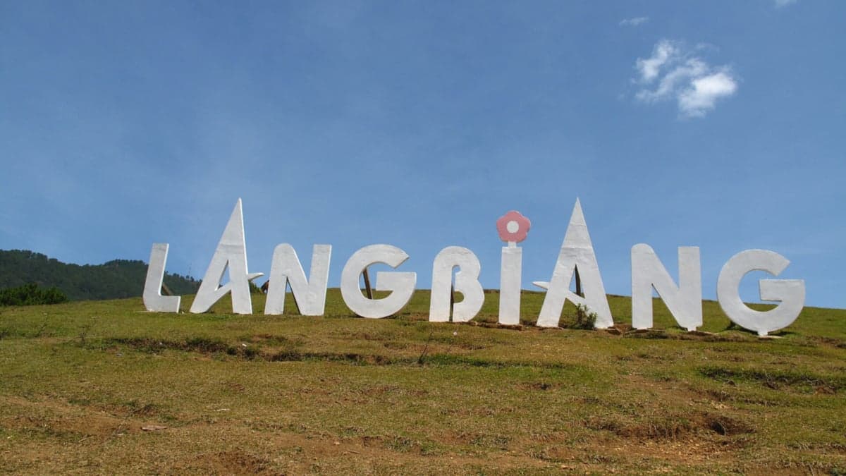 Dòng chữ LANGBIANG màu trắng trên đồi cỏ dưới bầu trời xanh