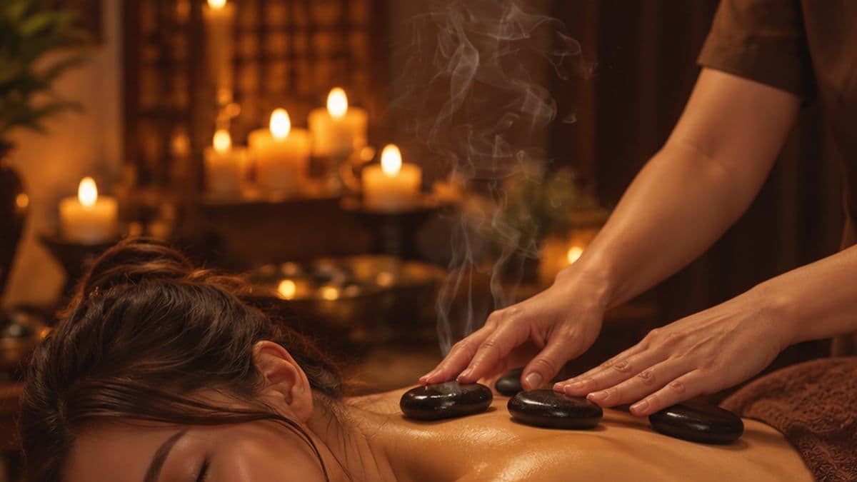 Kỹ thuật viên đặt đá nóng lên lưng khách, hơi nóng bốc lên trong ánh nến
